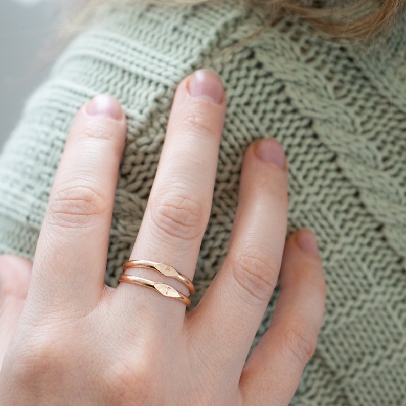 K&ouml;nnte beinhalten: Zwei d&uuml;nne goldene Ringe, die auf einem Finger &uuml;bereinander liegen. Die Ringe sind schlicht und haben eine leicht geh&auml;mmerte Textur.