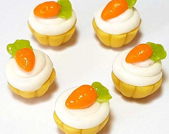 Peut inclure: Cinq petits cupcakes avec un glaçage blanc, des bases jaunes et des décorations de carottes oranges et de feuilles vertes. Les cupcakes sont disposés en cercle sur un fond blanc. Les détails des carottes et des feuilles sont clairement visibles.