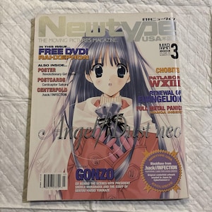 Puede incluir: Una portada de la revista Newtype USA con una ilustración de anime de una chica con pelo largo azul y ojos grandes. La portada incluye texto como "RAHXEPHON", "GONZO" y "MAR 2003."