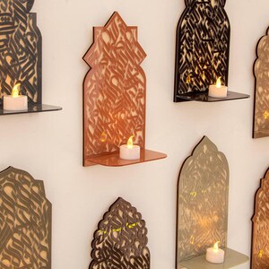 Peut inclure: Une collection d'étagères décoratives murales avec des motifs découpés au laser complexes. Chaque étagère présente une couleur et un motif différents, avec une petite bougie sur chaque étagère. Les étagères sont en bois et ont un design moderne et minimaliste.