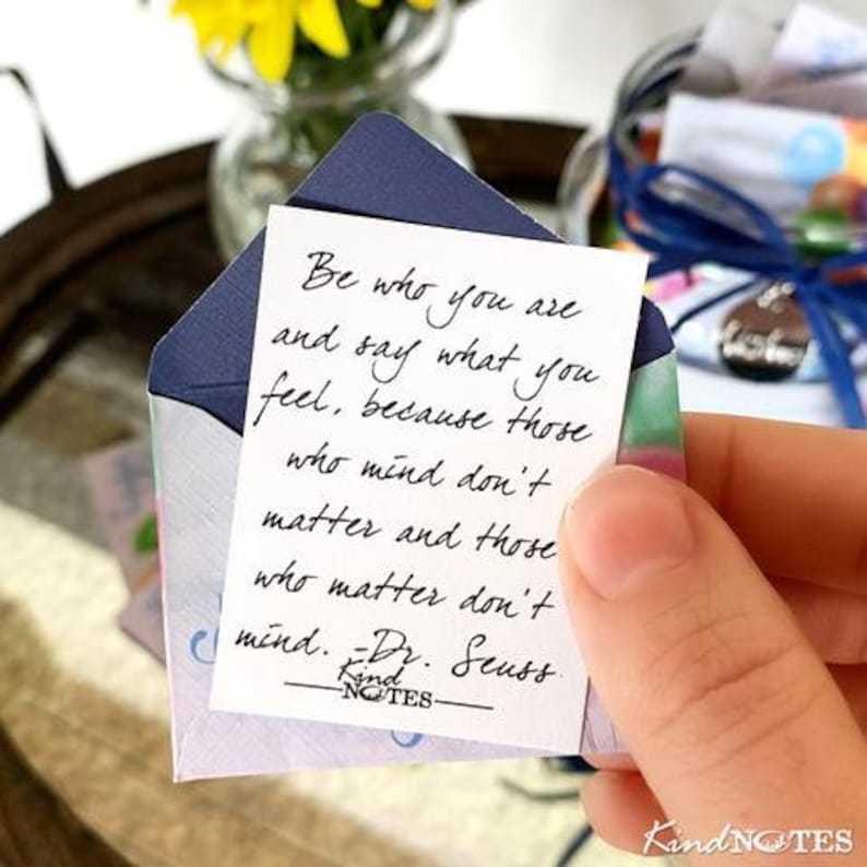 Op de afbeelding: Een witte kaart met blauwe en groene accenten, met een handgeschreven citaat van Dr. Seuss: "Wees wie je bent en zeg wat je voelt, want degenen die er iets van vinden, doen er niet toe, en degenen die ertoe doen, vinden er niets van." De kaart is gelabeld met "Kind NOTES".