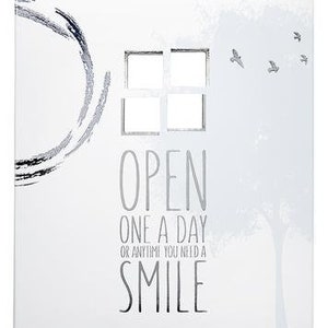 Op de afbeelding: Witte doos met een zilveren ontwerp en de tekst "OPEN ONE A DAY OR ANYTIME YOU NEED A SMILE".