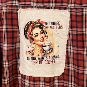 May include: Red and black plaid shirt with a white patch featuring a vintage illustration of a woman holding a coffee cup. The patch reads "Of course size matters" and "No one wants a small cup of coffee."