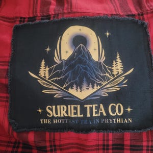 Upcycled Abracombie and Fitch Buffalo Plaid Flannel “Suriel Tea Co. The Hottest Tea in Prythian” black fringed graphic back patch Sz. small