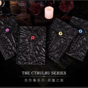 May include: Four black, textured books with colored eye designs, part of "The Cthulhu Series." Each book features a different eye color: purple, red, yellow, and blue. The books are arranged on a dark surface with candles and roses.