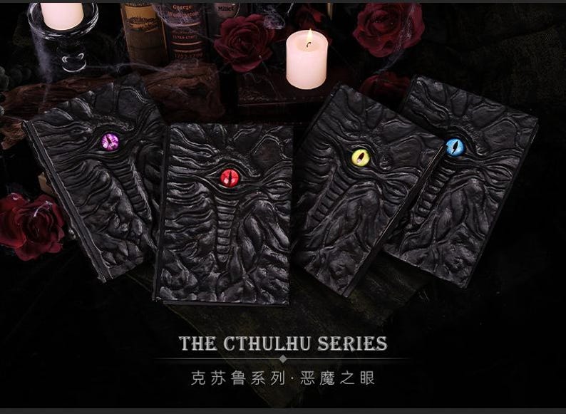 May include: Four black, textured books with colored eye designs, part of "The Cthulhu Series." Each book features a different eye color: purple, red, yellow, and blue. The books are arranged on a dark surface with candles and roses.