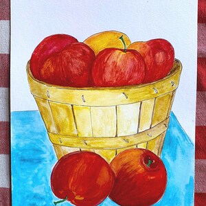 May include: A watercolor painting of a basket filled with red and yellow apples. The basket is made of woven wood and has a light brown color. The apples are arranged in a pile, with some spilling out of the basket. The background is a light blue color.