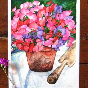 May include: Watercolor painting of a terracotta pot overflowing with pink, red, and purple sweet pea flowers. A gardening trowel rests beside the pot on a white tablecloth. A single purple flower is in the lower left corner.