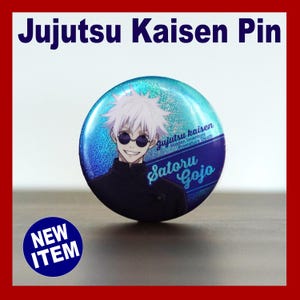 May include: A round pin with a blue and silver glitter background featuring an anime character with white hair and sunglasses. The pin has the text "Jujutsu Kaisen Pin" and "Satoru Gojo". A blue circle with "NEW ITEM" is in the lower left.