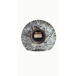 May include: A clear, faceted crystal clock with a circular design and radiating geometric patterns. The center features a dark circular face with the text Waterford Crystal and a small rectangular digital display screen in the middle.