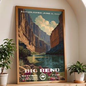 May include: A framed poster featuring a vintage-style illustration of Big Bend National Park. The artwork depicts a canyon landscape with a river, under a blue sky. Text includes "ESTABLISHED JUNE 12, 1944" and "BIG BEND NATIONAL PARK". The frame is made of wood.