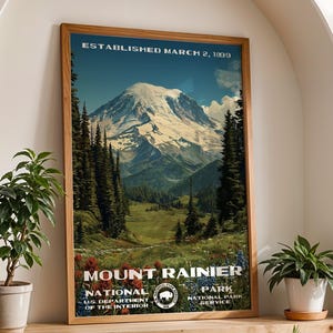 May include: A framed poster featuring Mount Rainier National Park. The poster has a vintage design with the text "ESTABLISHED MARCH 2, 1899" at the top. The image depicts a snow-capped mountain, trees, and a meadow. The bottom of the poster reads "MOUNT RAINIER NATIONAL PARK".