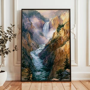 May include: A framed vertical wall art print depicting a landscape painting of a waterfall cascading into a river flowing through a deep canyon. The scene features golden-hued rocky cliffs, evergreen trees, and soft mist in a painterly style.