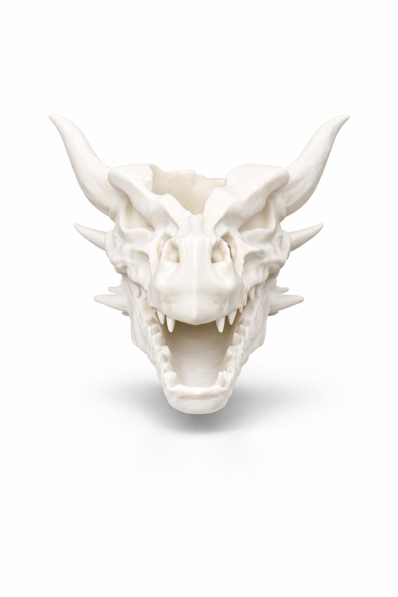 Front-facing view of a dragon skull head planter with open mouth, showing horn details and sculpted teeth.