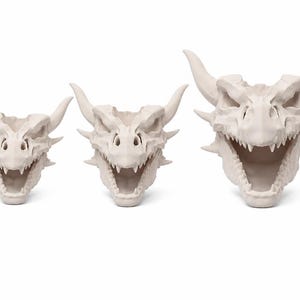 Three dragon skull planters in small, medium, and large sizes displayed front-facing with open mouths and horned details on a white background.