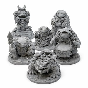 May include: A collection of gray fantasy miniatures depicting anthropomorphic frogs. The figures include a frog statue, a frog with a staff, a frog with a drum, and a frog with a spear. The miniatures are on circular bases.