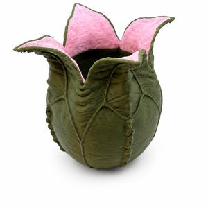 May include: A sculptural vessel shaped like an opening flower bud with a textured, dark olive green exterior featuring raised vein-like ridges and a contrasting soft, light pink interior lining that extends over the four pointed petals.