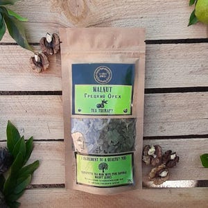 Pode incluir: Um pacote de chá de papel castanho com o texto "Walnut" em inglês e grego. O pacote está sobre uma superfície de madeira com nozes e folhas verdes. O chá está rotulado como "Tea Therapy".