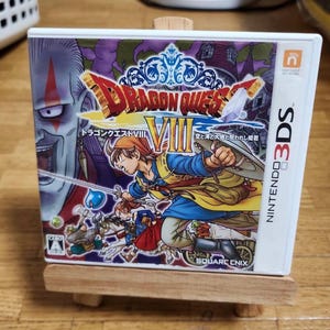May include: Dragon Quest VIII Nintendo 3DS game case. The cover features a dynamic illustration of characters in action, with the title in gold and blue. The game case is white with the Nintendo 3DS logo on the side.