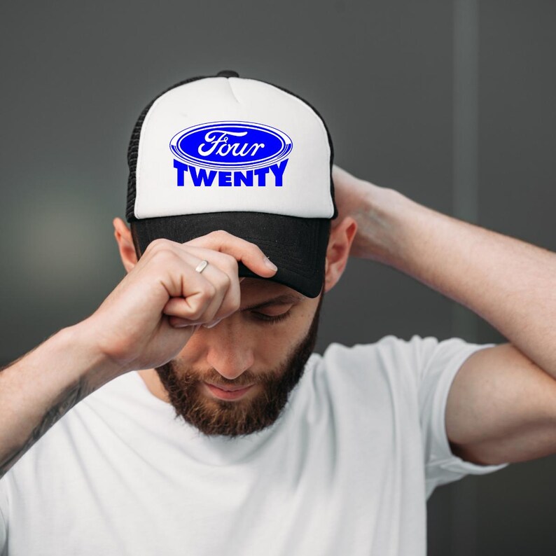 Op de afbeelding: Zwarte en witte truckerpet met de tekst "Four Twenty" in blauw. De pet heeft een wit voorpaneel met een blauw ovaal logo en een zwarte mesh achterkant. De pet wordt gedragen.