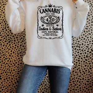 K&ouml;nnte beinhalten: Wei&szlig;es Sweatshirt mit schwarzem Grafikdesign. Der Aufdruck lautet: "CANNABIS HIGH TIME Old 420 BRAND QUALITY Indica & Sativa 100% NATURAL GROWN LOCALLY ALL OVER THE GLOBE."