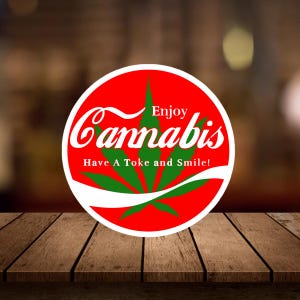 May include: A circular red and white graphic with the word "Cannabis" in white script. A green cannabis leaf is in the center. The text "Enjoy" and "Have A Toke and Smile!" are also included.