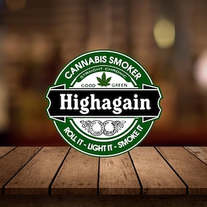 May include: A green and black logo with the words "Cannabis Smoker" and "Highagain". The logo includes a cannabis leaf and the phrases "Roll it - Light it - Smoke it". The background is blurred.