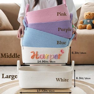 May include: A stack of four rectangular rope baskets in pink, purple, blue, and white. The white basket has the name "Harper" embroidered on it. The baskets are 14.96 inches (38cm) and 17.72 inches (45cm) wide, and 6.3 inches (16cm) high.