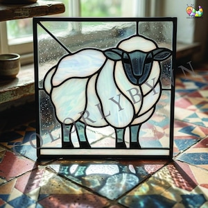 Könnte beinhalten: Quadratische Glasmalerei mit einem Schafmotiv. Das Schaf hat einen weißen, strukturierten Körper mit schwarzen Umrissen und einem dunkelgrauen Gesicht. Die Tafel ist schwarz umrandet und vor einem gesprenkelten Hintergrund platziert. Das Panel steht auf einer gemusterten Fliesenoberfläche.