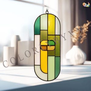 May include: A stained glass window hanging with a black metal frame. The window features a geometric design with shades of green, yellow, and white. The text "COLOR BY VV" is visible in the image.