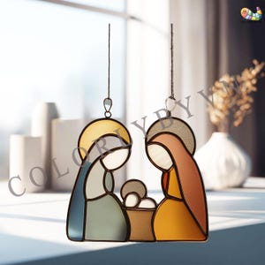 Può includere: Vetrata raffigurante la Sacra Famiglia, con Maria, Giuseppe e Gesù bambino. Le figure sono delineate in nero con pannelli colorati blu, giallo, marrone e arancione. L'opera è sospesa da un sottile filo metallico, adatta per essere appesa.