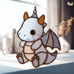 May include: A stained glass dragon ornament with a cartoonish design. The dragon features a white body, brown accents, and large, dark eyes. The wings are a mix of gray and white. The ornament is hanging from a metal loop.