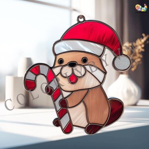 Pode incluir: Um enfeite de vitral com uma lontra de desenho animado usando um gorro de Papai Noel e segurando uma bengala doce. A lontra tem pelo marrom, rosto branco e detalhes vermelhos. A bengala doce tem listras vermelhas e brancas.