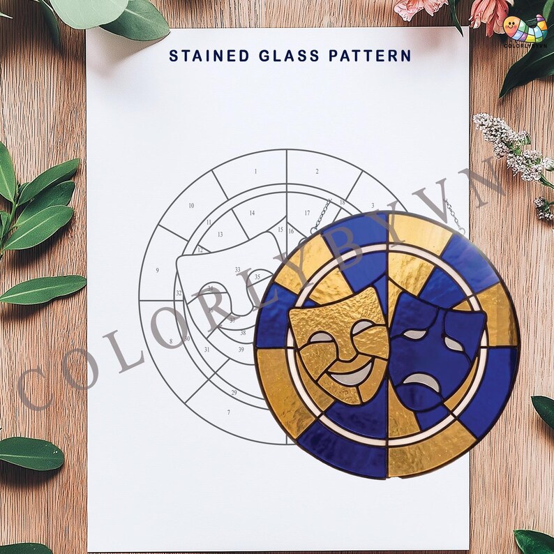 May include: A stained glass pattern featuring comedy and tragedy masks in gold and blue. The masks are set within a circular design, with a chain for hanging. The background shows a line drawing of the same design, with the text "STAINED GLASS PATTERN".