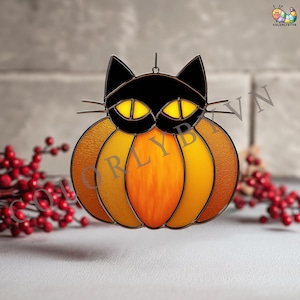 Peut inclure: Décoration d'Halloween en vitrail représentant un chat noir sur une citrouille. Le chat a des yeux jaunes et des moustaches. La citrouille est orange et jaune avec un aspect texturé. Une petite boucle est en haut pour accrocher.