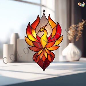 以下が含まれることがあります： 赤、オレンジ、黄色を基調としたステンドグラスのフェニックスサンキャッチャー。鳥は翼を広げ、細部までこだわった体で描かれています。サンキャッチャーは吊り下げて光を捉え、カラフルなディスプレイを作り出すように設計されています。