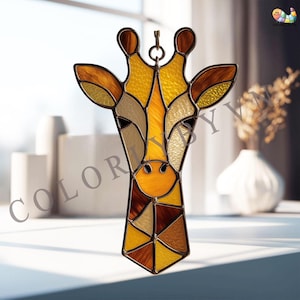 Könnte beinhalten: Glasmalerei Giraffenkopf mit Metallrahmen. Die Giraffe hat Gelb-, Braun- und Beigetöne. Die Giraffe hat oben eine Schlaufe zum Aufhängen. Der Hintergrund ist verschwommen, mit einem Fenster und Vasen sichtbar.