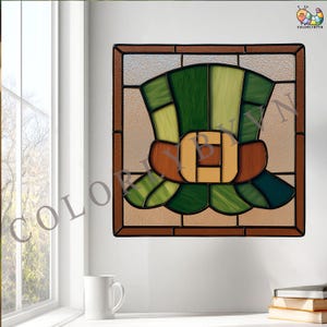 May include: Stained glass panel featuring a green and brown leprechaun hat design. The hat has a brown band with a gold buckle. The panel is square with a brown border and is suitable for window or wall decor.