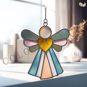 May include: Stained glass angel ornament with a yellow heart, multi-colored wings, and a halo. The angel's wings feature green, pink, and blue glass. The ornament is designed to hang and is framed with a dark metal.