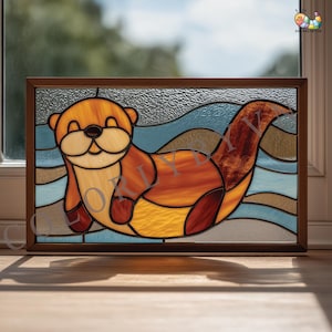 Pode incluir: Painel de vitral com uma lontra sorridente em tons de laranja, amarelo e castanho, sobre um fundo de água azul e bege. A obra de arte é emoldurada em uma moldura de madeira castanha escura, ideal para decoração de casa.