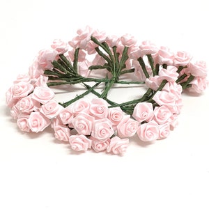 May include: A bunch of 30 small pink satin roses with green stems. The roses are arranged in a circle.