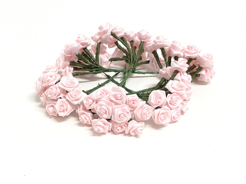 May include: A bunch of 30 small pink satin roses with green stems. The roses are arranged in a circle.