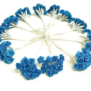 May include: A bouquet of 12 small blue satin roses on wire stems. The roses are arranged in a circle.