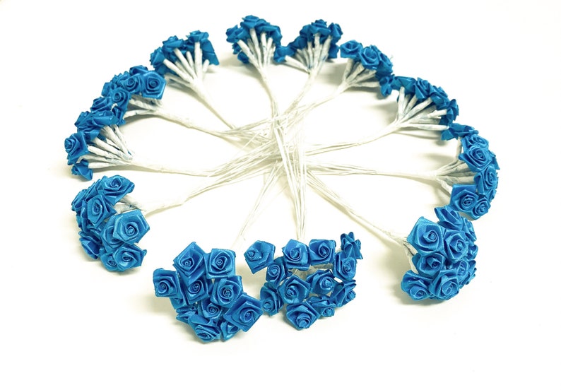 May include: A bouquet of 12 small blue satin roses on wire stems. The roses are arranged in a circle.