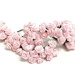 May include: A bunch of small, pale pink satin roses with green stems. The roses are arranged in a cluster, with some of the stems overlapping.