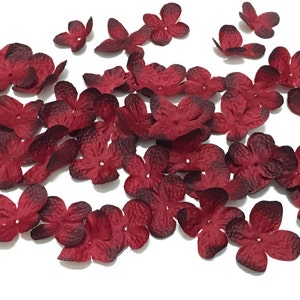 以下が含まれることがあります： 濃い赤色のフェルトの花びらがたくさんあります。花びらは中央が少し暗く、表面がざらざらしています。