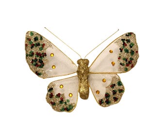 May include: A decorative butterfly with white wings and a gold glitter body. The wings have gold glitter accents with red and green details. The butterfly has small yellow embellishments.