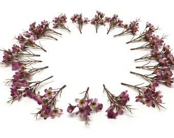 May include: A circle of small purple flower sprigs arranged on a white background.