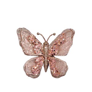 May include: A decorative butterfly with glittery wings in shades of pink and gold. The butterfly has a detailed design with a textured appearance, perfect for adding a touch of sparkle to any decor.