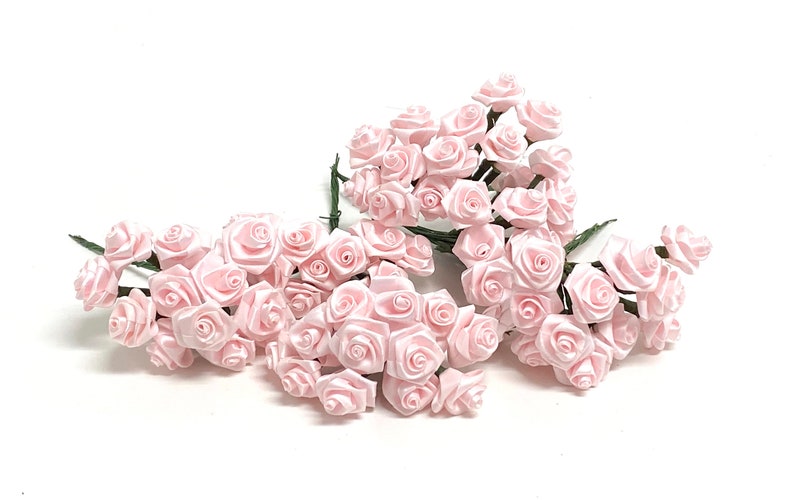 May include: A bunch of pale pink satin roses with green stems. The roses are arranged in a cluster, with some of the stems overlapping.